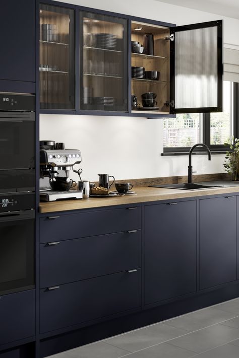 Looking for blue kitchen inspiration? Our Howdens Hockley Super Matt Navy In-Frame Kitchen is perfect for your blue kitchen ideas. The oak worktop, matt black tap and fluted glass kitchen doors are perfect for creating a navy kitchen design. Add your favourite home decor and kitchen appliances. Black Glass Kitchen Cabinets Modern, Kitchen Black Glass Cabinets, Black Kitchen With Glass Cabinets, Navy Kitchen Glass Cabinets, Black Kitchen Glass Cabinets, Kitchen Interior Navy Blue, Navy Kitchen Modern, Navy Kitchen Black Appliances, Blue Black Kitchen Cabinets