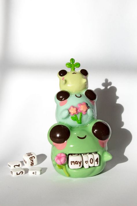 Cute spring frogs cuties holding flowers and sprout perpetual calendar perfect for desk and home decoration. Comes with clay basket and clay cubes for the months and numbers. ✿ d i m e n s i o n s ✿ Weight: 8 oz Height:  4.5 in Width: 2.5 in ✿ p r o c e s s ✿ This is a handmade creation, meticulously crafted with air dry clay. They undergo a process of sculpting, sanding, painting, and glazing right in home. Due to their artisanal nature, slight variations in color or shape are part of the charm, ensuring that each piece is truly one-of-a-kind! ✿ c a r e ✿ While air dry clay is robust, it's essential to handle it gently. Avoid bending or twisting the piece, and take care to prevent dropping them on hard surfaces. Limit exposure to water and keep them away from oils, lotions, and perfumes t Air Dry Clay Ideas Home Decor, Clay Female Figures, Air Dry Clay Axolotl, Cute Sculpting Ideas, Air Dry Clay Mini Figures, Air Dry Clay Cottagecore, Polymer Clay Pictures, Clay Office Decor, Cute Polymer Clay Ideas Kawaii