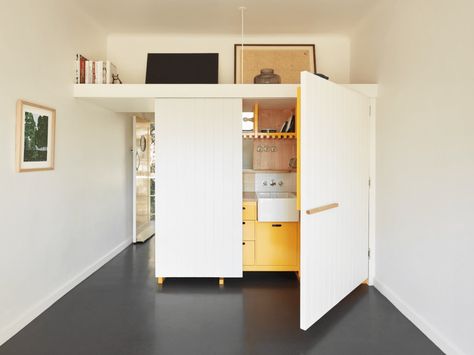 Micro-Apartments in Australia | Never Too Small Raised Platform Bed, Black Tile Bathrooms, Block Out Curtains, Bed Nook, Matte Black Kitchen, Micro Apartment, Ceiling Storage, Black Countertops, Pantry Shelving