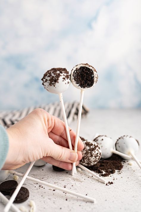 A hand holding two cookies and cream cake pops. Starbucks Cookies And Cream, Cookies And Cream Cake Pops, Cookie Pops Recipe, Starbucks Cookies, Starbucks Cake Pops, Starbucks Cake, Cooking With Karli, Cranberry Bliss Bars, White Chocolate Candy