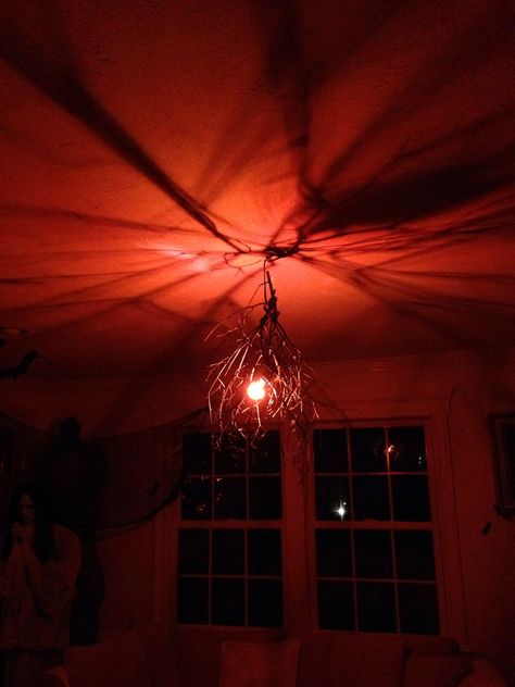 Orange light bulb with some black spray painted branches. Easy and super spooky.  Halloween Spray Painted Branches, Halloween Lights Indoor, Halloween Ceiling Decorations, Season Wheel, Orange Light Bulb, Voodoo Swamp, Hamlet Machine, Spooky Lighting, Halloween Ceiling