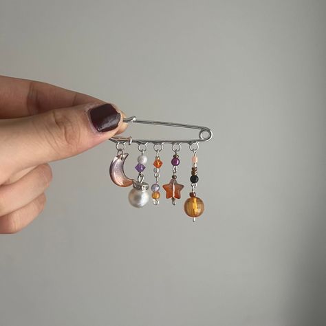 This is a space themed pin accessory that can be attached like a regular safety pin. It features a heavy-duty pin, several unique beads of all colors and sizes, and special charms including a star, moon, and dangling pearl. This product is handmade with high detail and care, and makes a great gift for birthdays, holidays, or any occasion! Crafts With Washers, Pin Charms, Gifts Handmade Ideas, Pin Beads Ideas, Safety Pin Bead Art, Craft With Beads, Things To Do With Safety Pins, Pin Keychain, Space Themed Accessories