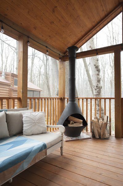 Jorie asked for an enclosed deck at the front of the home, which includes a dining area, as well as a space for the kids to sleep, if they desire. "The huge screen deck feels bigger than the interior of our home," she says. Tiny Home With Screened Porch, Screen Porch With Wood Burning Stove, Wood Stove On Screened Porch, Four Seasons Room With Wood Stove, Wood Stove Screened Porch, Fireplace On Front Porch, Wood Stove Patio, Covered Deck Extension Ideas, Screened In Porch With Wood Stove