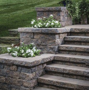 Stair or step planters can take a variety of shapes and styles. Options can include symmetrical tiers, terraced landings, or a singular accent planter. #planter Front Porch Stone Steps, Front Porch Stone, Backyard Retaining Walls, Patio Stairs, Front Door Steps, Front Porch Steps, Landscape Stairs, Patio Steps, Sloped Backyard