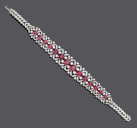 RUBY AND DIAMOND BRACELET, ca. 1950. White gold 750, 38g. Of floral design, set with 14 graduated, round rubies of ca. 6.00 ct, brilliant-cut diamonds weighing ca. 2.50 ct and decorated with diamond-set leaf motifs totalling ca. 1.80 ct. L