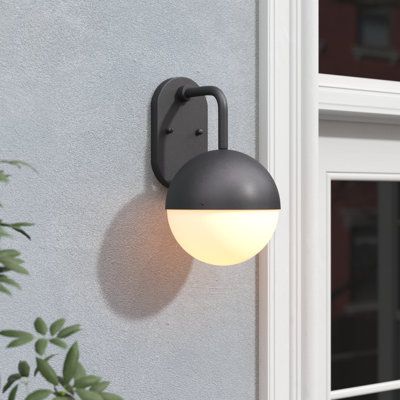 This outdoor wall lantern brings a layer of mid-century style outside your front door or in your garage. Crafted from metal, this fixture features a black-finished dome that matches the color of the backplate. The frosted glass shade on the bottom both establishes that retro vibe and evenly diffuses the light from the included LED bulb. Measuring 9.5'' in diameter, this pendant is sized to easily be mounted in small spaces or paired together with other lights for a coherent look. It's also compa Outdoor Lighting For House, Mid Century Modern Outdoor Lighting, Exterior Sconces Front Door, Front Entrance Light Fixture, Black Exterior Light Fixtures, Modern Porch Light, Midcentury Modern Exterior, Exterior House Lights, Outdoor Globe Lights