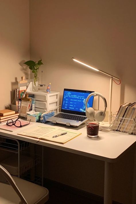 A minimalist study desk setup with a laptop, open notebook, reading lamp, headphones, and a calming candle. The desk also includes books, a plant, and organizational drawers, creating a warm and inviting space perfect for studying or working Simple Work Setup, Laptop Only Desk Setup, Small Tech Office Design, Minimalist Laptop Setup, Notebook Desk Setup, Small Cozy Desk Setup, Uni Desk Setup, Laptop Desk Setup Small Spaces, Desk Risers Ideas