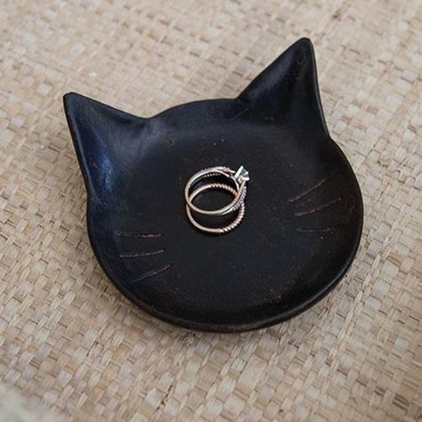 The Black Cat Tray is a shallow black resin tray in the shape of a cat face. The tray is made complete with subtle distressed details and whisker indents. This tray makes a great gift and can be used to hold jewelry, keys, or other small trinkets. Measures 1" high by 4" long by 3.75" wide. Cat Clay Tray, Black Cat Pottery, Cat Jewelry Holder, Clay Jewelry Tray, Cat Ashtray, Trinkets Dish, Cat Trinket Dish, Black Clay Pottery, Ceramics Cat