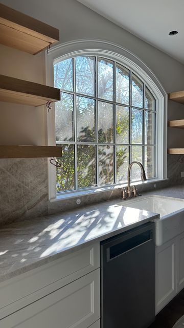 Andrew Roby on Instagram: "That natural light ☀️👌  As we bring the plans to life, we can’t help but pick out our favorite design elements in each renovation. This kitchen window is definitely one of our favorite features.   Design Architect: @charlotteinvironments . . . #kitchenrenovation #renovation #beforeandafterkitchen #openshelving #openshelvingkitchen #kitchenwindow #interiordesign #neutralkitchen #kitchendesign" Arch Window Kitchen Sink, Arched Opening Kitchen, Kitchen With Picture Window, Big Window In Kitchen, Large Window In Kitchen, Arched Kitchen Window, Windows Above Kitchen Sink, Window Backsplash Kitchen, Large Kitchen Window Over Sink