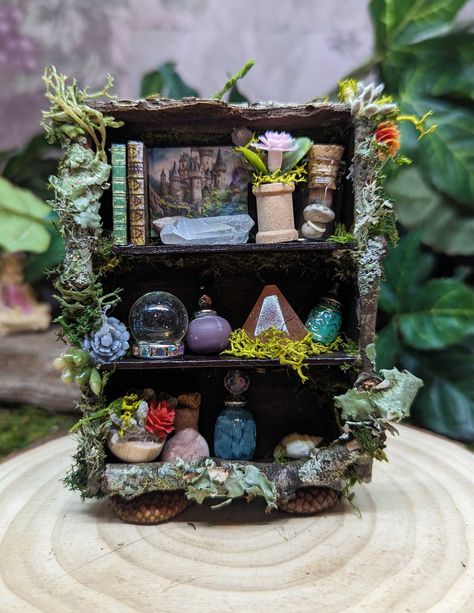 "Due to the items we use for this piece, this is really made for the inside fairies.  One of a kind handcrafted Fairy Bookshelf. Same fun items as our other bookshelves, but with a slightly different style. This one-of-a-kind fairy shelf is designed by the fairies - crafted by me! This piece will be handcrafted when ordered and bottles and little shelf accessories may vary slightly from the photo depending on what we have in stock. We make all of our special bottles and shelves in our workshop a Fairy Garden Shelf, Fairy Garden Book Nook, Fairy House Furniture Diy, Air Dry Clay Fairy Garden Accessories, How To Make Fairy Garden Accessories, Fairy House Diy Natural Materials, Fairy Crafts For Adults, Fairy House Interior, Fairy Furniture Diy