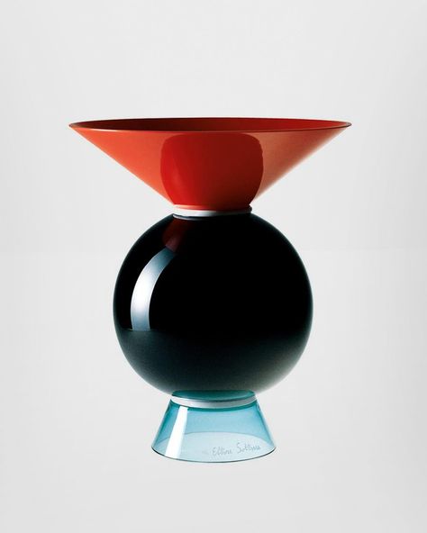 Yemen glass vase, designed by Ettore Sottsass and manufactured by Venini, features a geometric, circular shaped body and triangular neck and base. Featured in coral red, milk-white, black and light green colored glass. Originally designed in 1994. Indoor use only. DIMENSIONSØ 9.84" cm, H 11.81"Ø 25 cm, H 30 cm LEADTIME Most Venini products are made-to-order with a lead time of 4-6 weeks ex-factory; selected products may however be in stock. Please inquire with us for details. Geometric Vase Design, Geometric Product Design, 90s Interior, L Shaped Corner Desk, Art Studio Organization, Fragrance Packaging, Elements And Principles, Alcohol Bottles, Black Vase