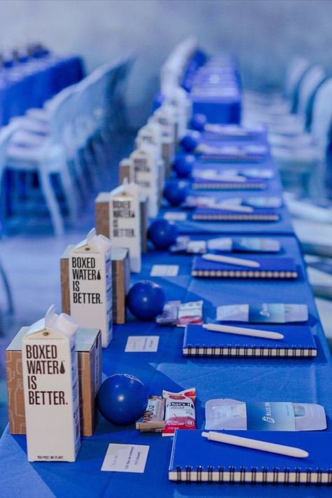 Explore this modern conference setup featuring sustainable boxed water and branded materials. This sleek and organized table arrangement showcases eco-friendly choices for a conscious event, highlighting the importance of sustainability in modern gatherings. #ConferenceSetup #SustainableEvent #EcoFriendly #BoxedWater #GreenGatherings Corporate Meeting Table Setting, Conference Centerpieces Business, Conference Decorations Events Table Settings, Corporate Event Centerpieces Simple, Conference Table Decorations Ideas, Conference Set Up, Sustainable Event Ideas, Corporate Event Decor Table Settings, Sustainable Event Decor