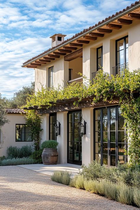 Modern Italian mediterranean house facade with vine covered pergola olive tree lined front yard. Check out all of these stunning Italian Mediterranean houses that encapsulate elegant arches, textured stucco, charming terra cotta details, and so much more. Spanish Home Windows, Santa Barbara House Style, Italian Inspired House Exterior, European House Style, Spanish Revival Courtyard, Modern Spanish Colonial Exterior, Desert Mediterranean Home, French Italian Homes, Mediterranean House Modern