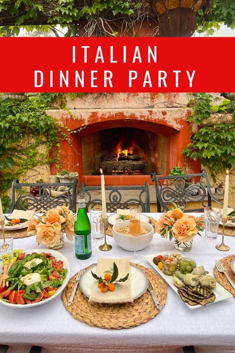 A beautiful dinner party set-up for 6 to 8 people. The table is set with a white linen table cloth in front of a rustic outdoor fireplace. On the table there is an antipasto platter and a large salad with burrata and tomatoes. The table setting includes peach-colored roses and gold candlestick holders with ivory taper candles. Italian Dinner Menu, Italian Food Party, Italian Dinner Party Decorations, Italian Christmas Dinner, Italian Food Menu, Vegetarian Dinner Party, Birthday Dinner Menu, Family Dinner Menu, Italian Themed Parties