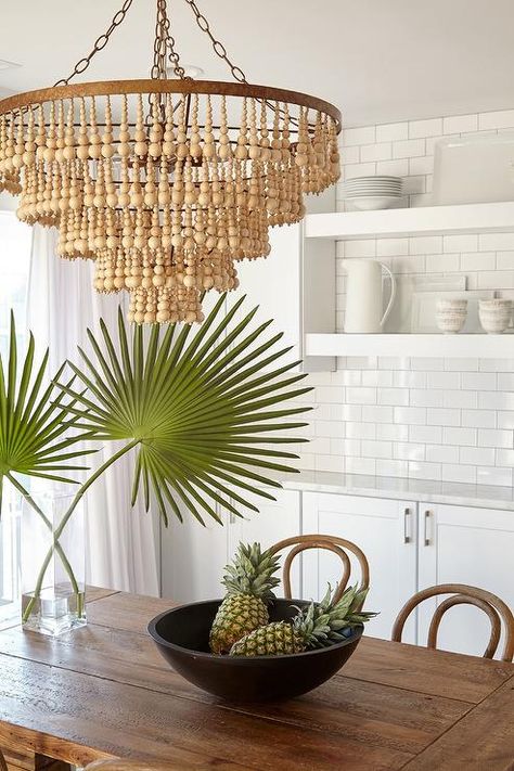 A beige wood bead chandelier hangs over a plank dining table surrounded by Bentwood chairs and placed in front of white shaker cabinets. Restful Bedrooms, Bead Chandelier, Wood Bead Chandelier, Beaded Lamps, Timeless Interiors, Beautiful Dining Rooms, Diy Chandelier, Bentwood Chairs, Deco Boheme