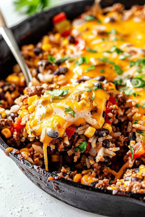 This one-pan taco skillet is a tasty meal no one can resist! It's loaded with ground beef, veggies, rice, black beans, corn, and plenty of cheese for a true fiesta. Essen, Nacho Skillet Ground Beef, One Pan Mexican Beef And Rice, Beef Skillet Fiesta, Diner With Ground Beef, Skillet Taco Rice, Corn Tortilla Ground Beef, One Pan Taco Rice, Healthy Ground Beef Skillet