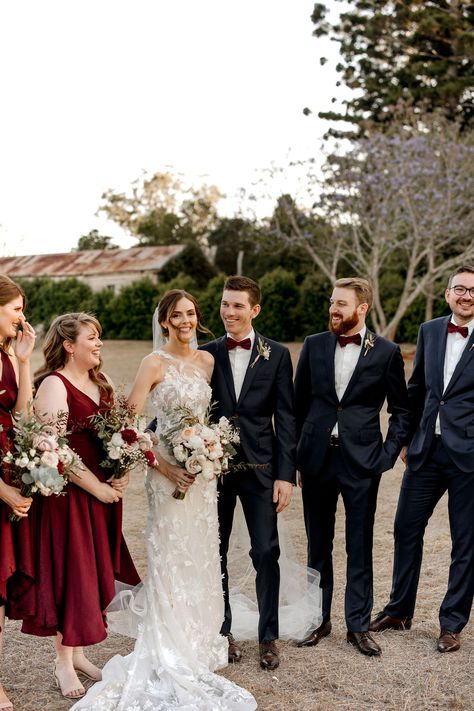 Seeing this bridal party all together is so cohesive and simply stunning. The burgundy of the bridesmaids dresses paired with the bow tie of the groomsmen is such a lovely touch. Black And Red Wedding Party Attire, Burgundy Bridal Party, Gabbinbar Homestead, Burgundy Bridesmaids, Bridal Campaign, Modern Bridal Party, Burgundy Wedding Theme, Maroon Bridesmaid, Maroon Bridesmaid Dresses