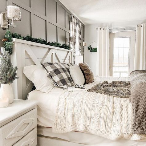 A farmhouse-style white wood headboard styled with pine garland is fitted with white and gray bedding. The bed stands in front of a gray board and batten accent wall next to a white nightstand. Bed Comforter Sets Farmhouse, Cozy Farmhouse Bedroom, Cream Bedroom, Rustic Farmhouse Bedroom, Farmhouse Bedroom Ideas, Farmhouse Style Bedrooms, Modern Farmhouse Bedroom, Farmhouse Master, Country Bedroom