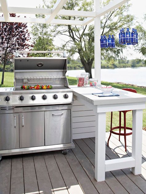 When space allows, add a countertop or island next to the grill to make food prep and service easier. A peninsula works well in this outdoor kitchen. It provides additional seating for outdoor dining that's close enough for the cook to chat with guests, but it keeps people away from a hot grill. Affordable Landscaping, Simple Outdoor Kitchen, Model Dapur, Outdoor Grill Station, Outdoor Kitchen Countertops, Design Tricks, Outdoor Kitchen Patio, Built In Grill, Diy Outdoor Kitchen