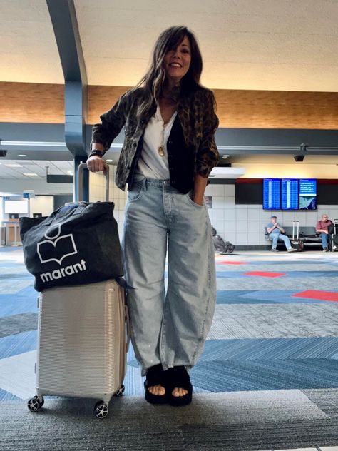 Woman posing at the airport dressed in barrel leg jeans, white shirt, black vest, and black sandals. Puddle Jeans Street Style, Barrel Pants Women, Barrel Denim Outfit, Baloon Jeans Styling Women, Barrel Jeans Outfit Spring, Diy Barrel Jeans, Ballon Jeans Outfits, Barrel Jeans Outfit Street Style, Barrel Leg Pants Outfit