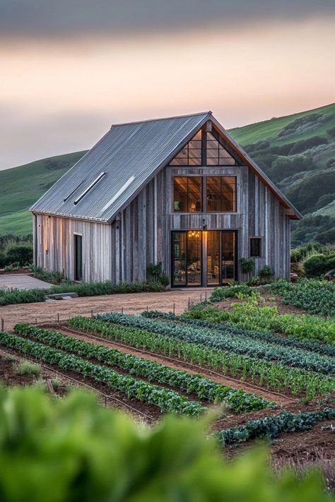 Modern barn style house facade with reclaimed wood accents on a farm with veggie gardens green hills in the background. Check out all of these creative and charming barn-style houses, blending rustic charm with modern functionality. These will change they way you look at barns completely. Barn With Greenhouse Attached, Old Barn Restoration, Barn Exterior Ideas, Educational Farm, Stone House Revival, Ranch Landscape, Rustic Barn Homes, Farm Garage, Farm Background