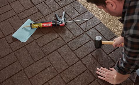 A man setting rubber pavers with a mallet. Rubber Pavers Ideas Patio, Recycled Rubber Pavers, Rubber Walkway, Diy Stone Walkway, Rubber Pavers, Rubber Paver, Paver Ideas, How To Install Pavers, Brown Tile