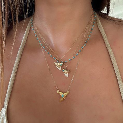 Turquoise Shark Tooth Necklaces. We know you will want to swim in the ocean with your shark tooth necklace so we used waterproof vermeil gold for this piece, and we always use authentic stones, so our turquoise is 100% real Arizona turquoise.The shark teeth we use are found on the shores of Florida and are all a bit different in size and shape. You will receive one shark tooth necklace. Gold with turquoise and white tip. Some photos show other pieces as layering options and styling inspiration. Gold Summer Jewelry, Gold And Turquoise Jewelry, Shark Tooth Necklace Gold, Swim In The Ocean, Surf Jewelry, Shark Necklace, Beachy Jewelry, Pretty Jewelry Necklaces, Shark Tooth Necklace