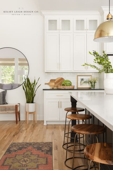 Kelsey Leigh Design Co brings the casual California vibe to this home in Edmond, OK. Through texture, organic materials and finishes, and earth tones, this kitchen gives the client the laid-back, casual feel of California style. The dark kitchen island contrasts nicely with the bright white kitchen cabinets. The pendant lights over the island provide just the right punch of style for this casual home. For more, visit kelseyleighdesignco.com #modernkitchen #kitchenideas #kitchendesign Montecito Style Kitchen, California English Decor, California Contemporary Kitchen, California Casual Interior Design Dining Room, Casual California Decor, California Casual Family Room, California Causal Interior, California Casual Style Home, California Aesthetic Interior Design