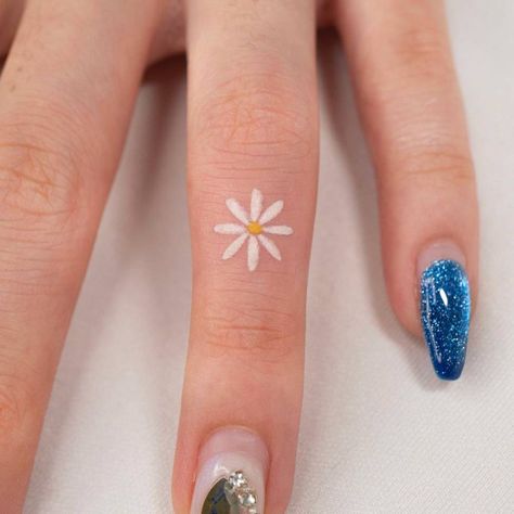 Minimalist daisy flower tattoo on the finger. Flowers On Finger Tattoo, Small Daisy Tattoo Color, Tiny Flower Finger Tattoo, Small Flower Tattoos Finger, Daisy Tattoo On Finger, Daisy Tattoo Finger, Micro Daisy Tattoo, Finger Tattoos Colorful, Daisy Small Tattoo