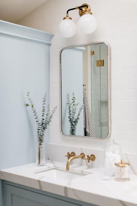 Two-light globe sconces light a curved nickel vanity mirror hung from a wall covered in white subway wall tiles. Pale Blue Paint Colors, Pale Blue Paint, Paint Colors Palettes, Nola Style, Blue And White Bathroom, Subway Tiles Bathroom, White Bathroom Designs, Spring Colours, Transitional Bathroom