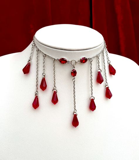 This bloody necklace features an array of glass faceted drops that hang from a stainless steel chain. The drops are also accompanied by gorgeous, high quality glass jewels which reflect light beautifully- perfect for blinding your prey. There are 2 chain length options available: Choker, the overall length is 16 inches including a 5 inch chain extender so that it can be worn between 11-16 inches. Standard Necklace, the overall length is 20 inches including a 5 inch chain extender so that it can be worn between 15-20 inches. Materials include; stainless steel, oxidised sterling silver plated brass and high quality glass. If you have any questions about this item, you are more than welcome to contact darklingbeloved@gmail.com Necklace Blood, Blood Necklace, Droplet Necklace, Vampire Necklace, Blood Drop, Goth Choker, Goth Necklace, Vampire Goth, Gothic Chokers