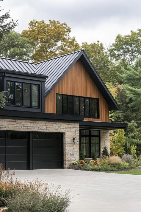 Modern farmhouse in mixed siding with black cedar stone multi pitched black roof modern windows with black trim cedar wood garage doors large. Ready to embrace the dark side of design? Get inspired by the bold, dramatic beauty of black houses. Dark Brown Cedar Siding Exterior Houses, Side Split House Exterior Remodel, Grey House Black Trim Wood Accents, Dark Gray Siding With Cedar Accents, Dark Brown Board And Batten Siding, Contemporary Farmhouse Exterior Design, Black Hardy Board Exterior, Dark Exterior Modern Farmhouse, Houses With Black Siding