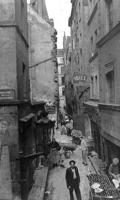 Chapter 2: She glanced up at the ancient buildings with disfavor. They seemed so disorganized, like a child’s toy blocks stacked haphazardly one upon the other. Small, crooked windows spoke of a time before glass, when waxed leather was all that kept the elements out. The spalling stone of the buildings themselves felt too old, too watchful. Even the modern gaslit street lamps didn’t help, casting shadows that flittered with the dance of the flame. Paris 19th Century, Paris 1800, France 1800s, 19th Century France, Paris History, Casting Shadows, Paris 1900, Paris Black And White, The Great