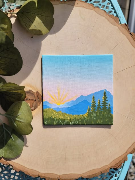 This original, hand-painted piece is a mini landscape scene painted in bright blues, forest greens, and a touch of sunny yellow. It was inspired by the crisp morning air and bright rays of sunshine you experience at sunrise in the mountains. This piece makes a great gift for your partner, friend, coworker, sibling, parent, or just for yourself! Display it on your desk at the office, on your dresser in your room, or on the wall in any room in your home 2 Inch Canvas Paintings, Cute Square Canvas Paintings, Outdoors Painting Ideas, Painting Ideas On Canvas Nature Easy, Mountain Simple Painting, Tiny Mountain Painting, 3x9 Canvas Ideas, Easy Mountain Landscape Painting, Small Nature Paintings