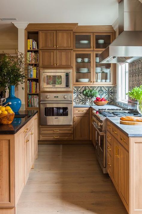 Strikingly beautiful caramel stained kitchen cabinets are accented with polished brass hardware and a concrete countertop fixed against ivory and blue mosaic backsplash tiles. Stained Kitchen Cabinets, Caitlin Moran, Patterned Tile Backsplash, Wall Kitchen, Cabinet Ideas, Hampton Bay, Transitional Kitchen, Cottage Kitchen, Counter Top