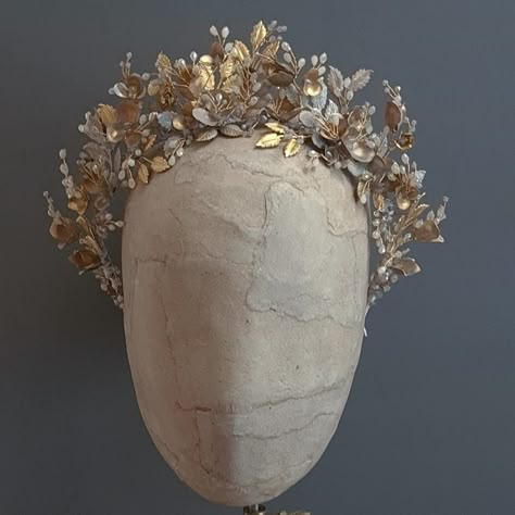 Pale grey and gold crown I made one of these crowns and it sold pretty much straight away so I made another one and it was featured in one of my favourite ever shoots (the one with three models wearing crowns a bit further down my posts). I’ve got enough flowers and leaves to make one more. I’ve used natural brass flowers and leaves and then I’ve enamelled them with a very pale grey enamel that, after firing, still shows shimmery gold underneath the grey and taupe tones. It’s a really lovel... Ivory And Gold Crown, Gold Leaf Crown Adora By Simona, Oak Leaf Tiara, Golden Leaf Crown, Greek Golden Leaf Crown, Bridal Accessories Jewelry, Gold Crown, Another One, Pretty Much