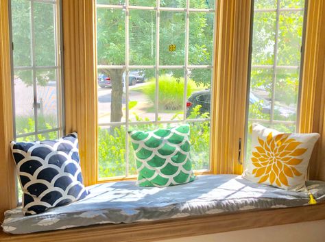 A window seat with a DIY boxed cushion with piping. Also shown are DIY stenciled pillows. Diy Bay Window Cushion, Diy Bay Window Seat Cushion, Bay Window Seat Diy, Diy Bay Window, Bay Window Seat Cushion, Bay Window Cushion, Diy Window Seat, Stenciled Pillows, Bay Window Seat