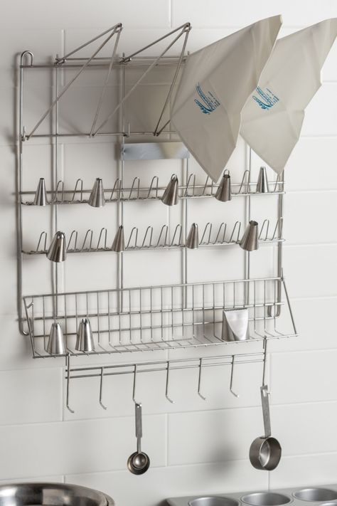 Kitchen organization is a top priority when trying to get your business to run smoothly. Whether you own a bakery or your restaurant has a top-tier pastry team, having a pastry bag and pastry tip drying rack is beneficial for cleaning and organization. This drying rack makes storage simple, too! Pot Storage Small Space, Anthropology Holiday Cooling Racks, Pantry Apron Hangers, Balcony Grocery Hoist, Soap Making Drying Racks, Bakery Organization, Bakery Layout, Baking Supplies Organization, Baking Room