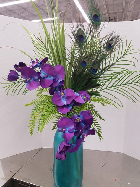 Orchids and peacock feathers Peacock Vase Arrangement, Centerpieces With Peacock Feathers, Peacock Arrangements Ideas, Arrangements With Peacock Feathers, Flowers With Peacock Feathers, Peacock Feather Arrangements, Peacock Feather Flower Arrangements, Peacock Flower Bouquet, Peacock Floral Arrangements