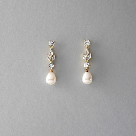 An off-white teardrop pearl hangs below glowing CZ leaf jewels in these classically made wedding earrings. These post-back pierced earrings are rhodium, gold, or rose gold plated, AAA grade CZ, synthetic pearl, measure 1.25 inches long and 3/8 of an inch wide, and are lead and nickel-free. Dangling Pearl Earrings Wedding, Gold Wedding Earrings Bride, Yellow Gold Wedding Earrings, Double Piercing Wedding Earrings, Gold Pearl Wedding Earrings, Pearl Jewelry Bridal, Bridal Earrings Multiple Piercings, Wedding Earrings Statement, Simple Bridal Accessories