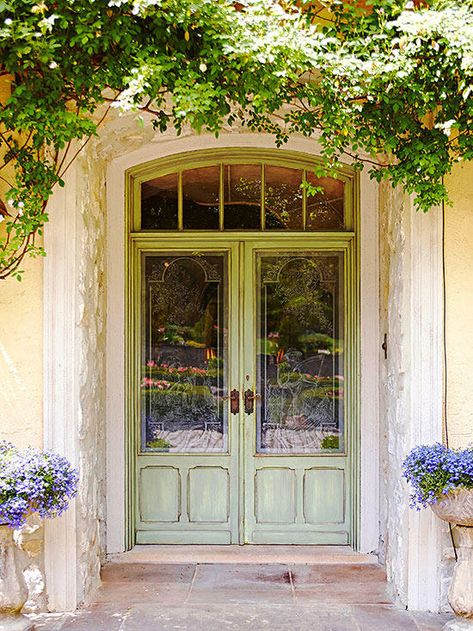 The prettiest details offer unmatched elegance against the washed-out paint finish of this mostly glass front door. Splendid in size, the double door relies on an excess of glass in both the doors and the five-paned transom overhead. While many standard doors are set flush onto the facade of a home, this one instead has a deep recess, boosting its romantic appeal. Statement Front Door, Bright Front Doors, French Front Doors, Front Door Makeover, Beautiful Front Doors, European Doors, Farmhouse Front Door, Double Front Doors, Front Door Entrance