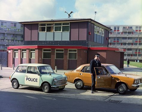 The Bay City Rollers, Mud and Showaddywaddy may have been riding high in the UK charts but it was just another day on patrol for this Greater Manchester Police officer back in 1975. He is photographed standing with two fine examples of the British motor industry. He uses the radio in an unmarked police Marina that is parked beside a classic Mini. www.gmp.police.uk British Police Cars, Morris Marina, Manchester Cathedral, British European Airways, Manchester Police, Salford City, Manchester City Centre, Bay City Rollers, British Motors