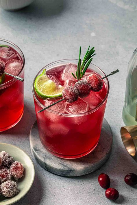 Made with cranberry juice, maple syrup and a splash of ginger beer, this Christmas gin cocktail is crisp and refreshing. We've garnished it with fresh rosemary and sugared cranberries for a festive, vibrant cocktail that will be the hit of your holiday gathering. Cranberry Ginger Beer Cocktail, Cocktail With Rosemary, Christmas Cocktail Garnish Ideas, Gin Punch Recipe Easy, Christmas Cocktail Garnish, Christmas Rum Drinks, Festive Cocktails Christmas, Gin Christmas Cocktail, Christmas Gin Cocktails