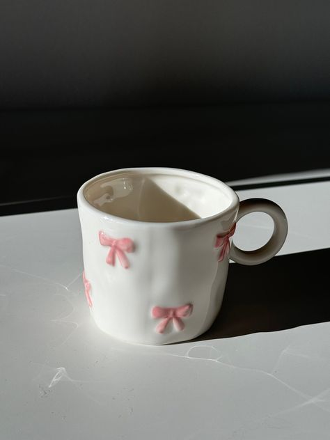 Say hello to the "Marie" Coquette Mug. Each ceramic mug is meticulously handcrafted and hand-painted, making every piece unique. For best care, we recommend hand washing to preserve the beauty and longevity of your Marie Coquette Mug. Elevate your morning routine or afternoon tea with this purr-fectly charming addition to your home. Diameter: 8cm  Height: 7cm Its a tiny mug but not super tiny! Cute Tea Gifts, Pottery Tea Mug, Dior Mug, Self Care Coquette, Cute Cup Aesthetic, Aesthetic Coffee Mugs, Coquette Ceramics, Mug Shapes Pottery, Bow Mug