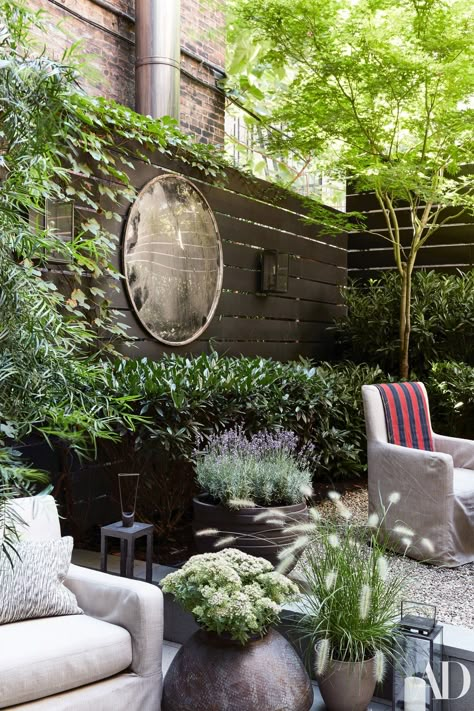 In the garden, designed by Harrison Green, custom armchairs by August Studios wear a Holly Hunt acrylic. Vintage highway mirror on wall. Small Patio Garden, Minimalist Garden, Courtyard Gardens, Garden Mirrors, East Village, Small Garden Design, New Garden, Little Garden, Courtyard Garden