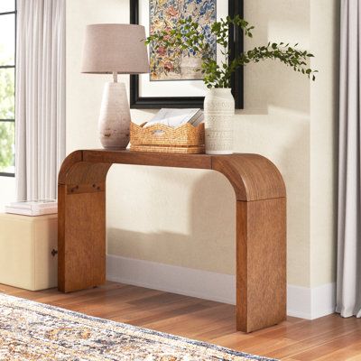 Infuse your entryway or living room with sleek, modern appeal, thanks to this distinctive, 52” wide console table. Crafted from kiln-dried solid and engineered wood in a warm, walnut tone hue that highlights the natural grain variation, it has a graceful, fluid shape, with rounded sides and a seemingly seamless finish. Style this table with eye-catching decor, a stack of coffee table books, and a lamp for a statement-making look. Assembly is required; all tools are included. Color: Brown | Three Curved Console Table, Curved Console, Living Tv, Wooden Console Table, Wooden Console, Wood Console Table, Entry Table, Wood Console, Coffee Table Books