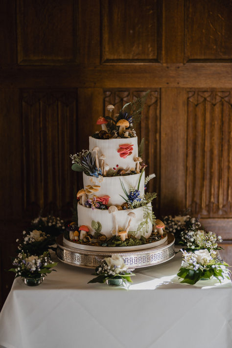 Three tier white iced wedding cake with whimsical cake design featuring colourful mushrooms and toadstools | whimsical wedding | magical wedding cake | wedding cake design | James Kimberley Photography Quirky Wedding Cake Toppers, Wedding Cake Cottagecore, Hobbit Wedding Cake, Fae Wedding Cake, Spring Whimsical Wedding, Fantasy Wedding Cakes, Enchanted Wedding Cake, Forest Themed Wedding Cake, Mushroom Wedding Cake