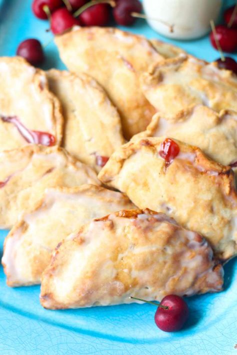 closeup of hand pies on a blue plate with cherries scattered around Cherry Hand Pies Recipes, Fruit Hand Pies, Fried Hand Pies, Cherry Hand Pies, Hand Pie Recipes, Fried Pies, Hand Pie, Cherry Recipes, Fresh Cherries