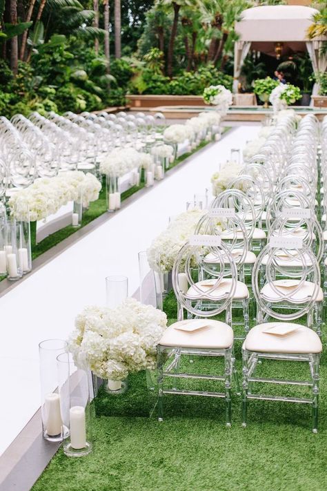 Dec 21, 2020 - Guests found their seats on oval-back acrylic chairs on both sides of a crisp white aisle lined with candles and arrangements of ivory hydrangeas in mirrored b… Sleek And Modern Wedding, Outside Wedding Ceremonies, Wedding Ceremony Chairs, White Wedding Ceremony, Ceremony Florals, White Wedding Decorations, Wedding Isles, Hydrangea Wedding, Tan Wedding