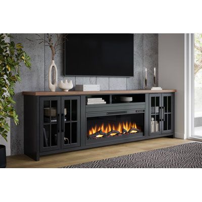 This TV stand comes with an electric fireplace insert that adds a cozy ambiance to your living room. A remote is included to control the heat output, the LED flickering flame effect, and the timer. Crafted from solid wood with a contrasting two-tone finish, this stand lends a modern farmhouse vibe thanks to its clean lines and the windowpane paneling on both cabinet drawers. Glass fronts let you look inside at your DVD or game collection, while two cubbies over the insert are ideal for consoles Large Tv Console With Fireplace, 72 Inch Electric Fireplace With Tv, Electric Fireplace Stand Alone, Modern Farmhouse Living Room Leather Sectional, Fake Fireplace Tv Stand, Electric Fireplace Furniture, Fireplace Console Decor, Electric Fireplace Ideas With Storage, Living Room Tv Stand Decor Ideas